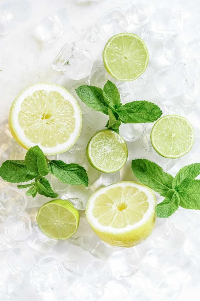 Fresh lemon, lime and mint with ice cubes – natural homemade electrolyte drink ingredients for hydration