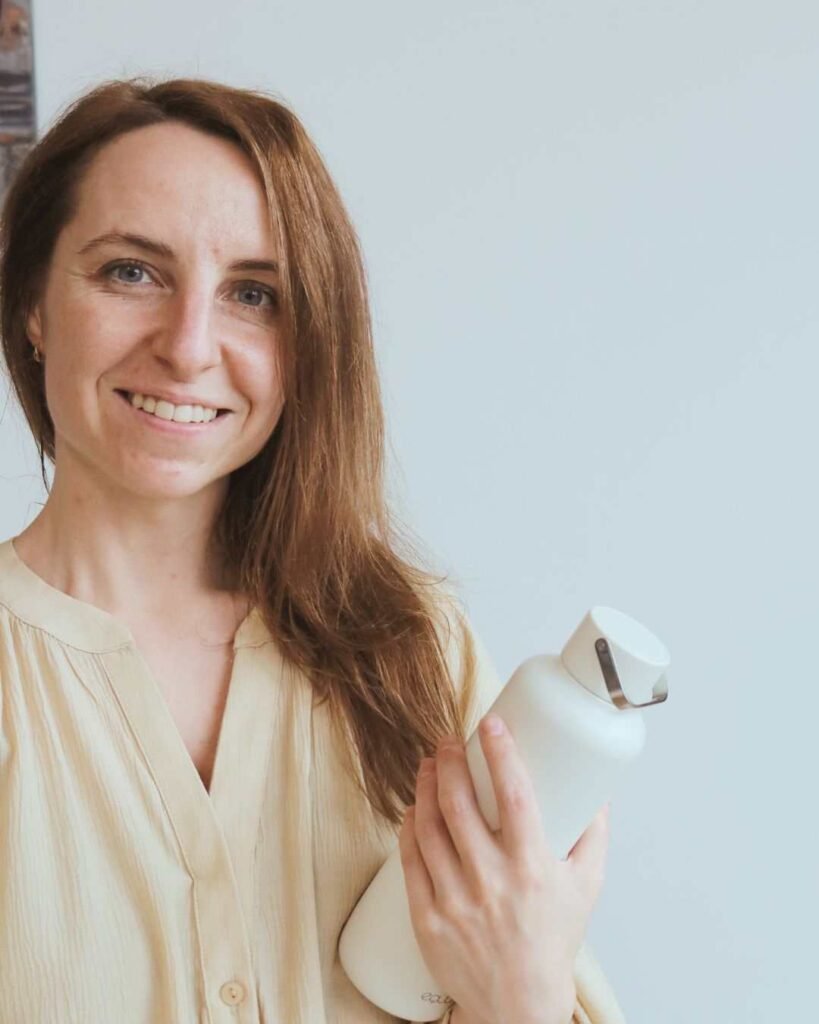 Smiling woman holding reusable stainless steel water bottle – eco-friendly hydration and healthy lifestyle choice